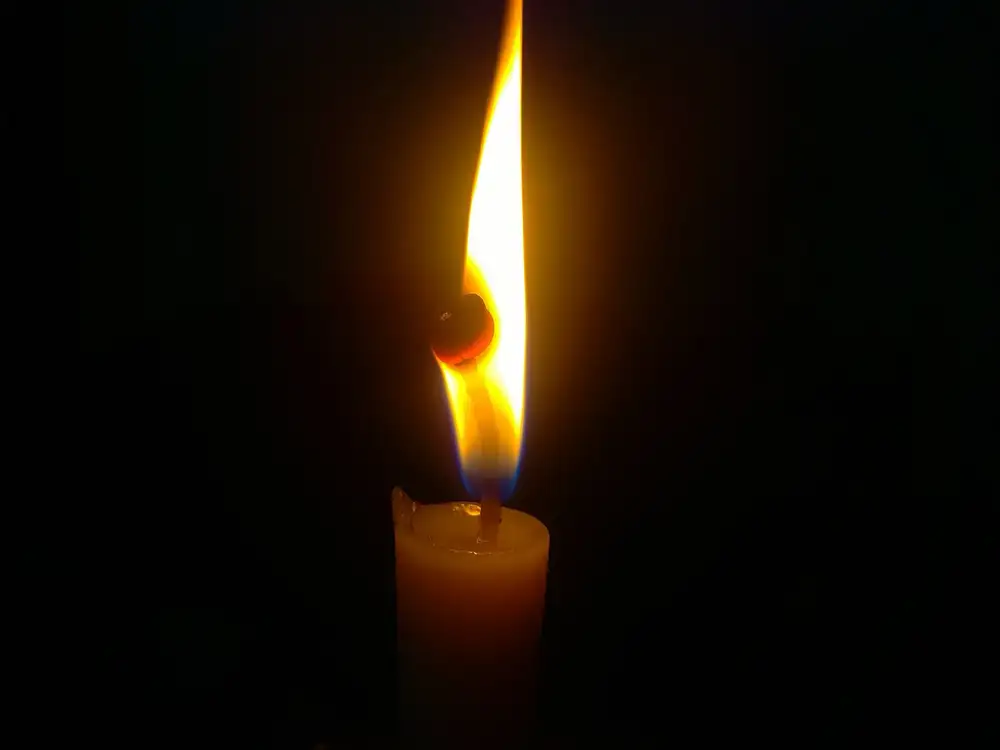 Una vela encendida en una habitación completamente a oscuras