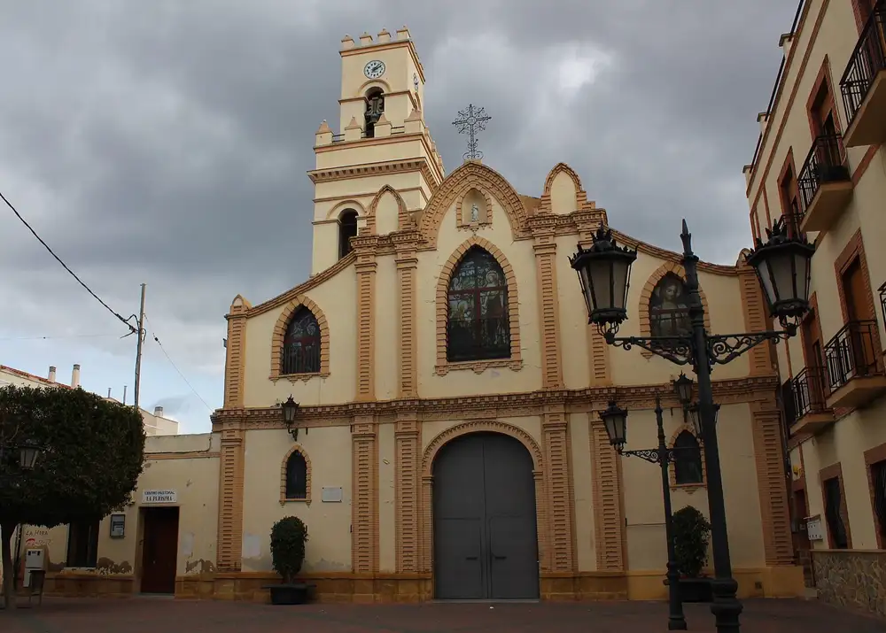 Fachada de la iglesia de La Purísima de El Palmar, con su torre del reloj y farolas en la plaza